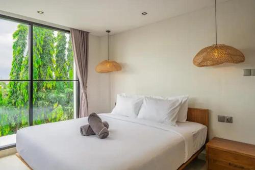 a bedroom with a large white bed with a window at Villa Casa Sea Salt in Denpasar