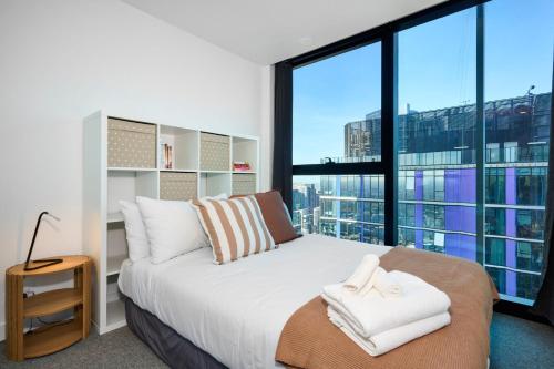 a bedroom with a bed and large windows at Stay Fit & Relax - 2BR with Gym & Spa in Melbourne
