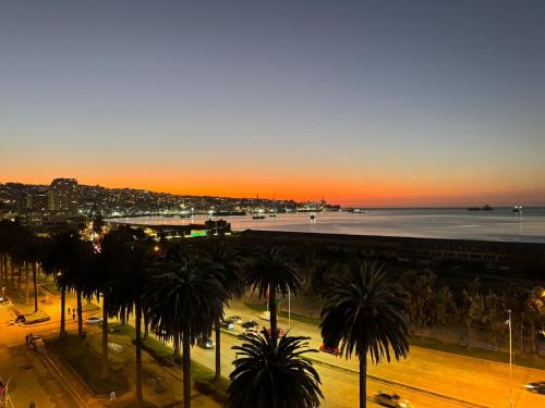 a city with palm trees and the ocean at sunset at Muelle Barón - Terminal de Buses in Valparaíso