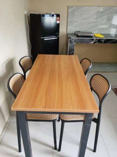 a wooden table with four chairs and a refrigerator at Homestay Che Wan Dua in Kuantan
