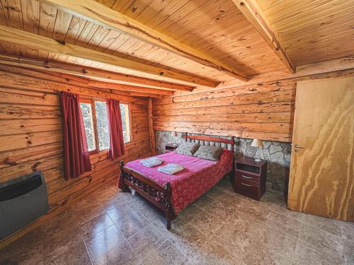 ein Schlafzimmer mit einem Bett in einer Blockhütte in der Unterkunft Apart al Lago in Villa Pehuenia
