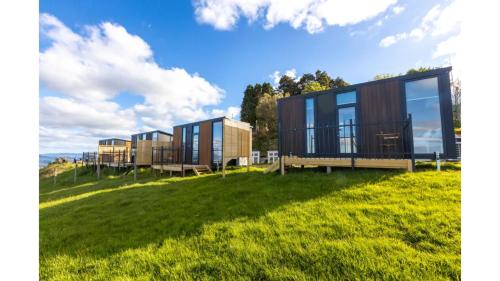 a row of modular houses on a grass field at Aorangi Peak Cabins 4 by Tiny Away in Rotorua