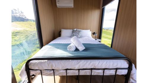 a bed in a room with a large window at Aorangi Peak Cabins 4 by Tiny Away in Rotorua