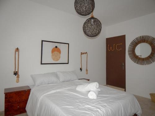 a bedroom with a bed with white sheets and a mirror at Eco Bay Surf Camp in Aourir