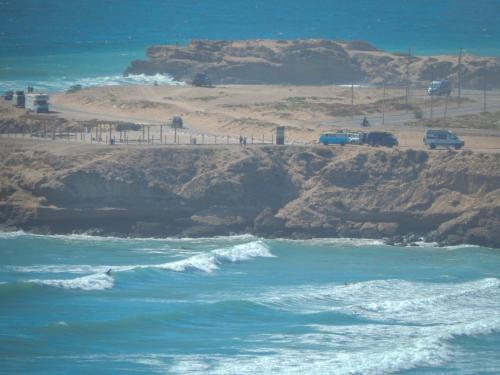 a view of the ocean and a beach with cars at Eco Bay Surf Camp in Aourir