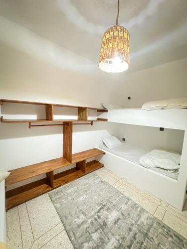 a room with white walls and a bed and a chandelier at Eco Bay Surf Camp in Aourir