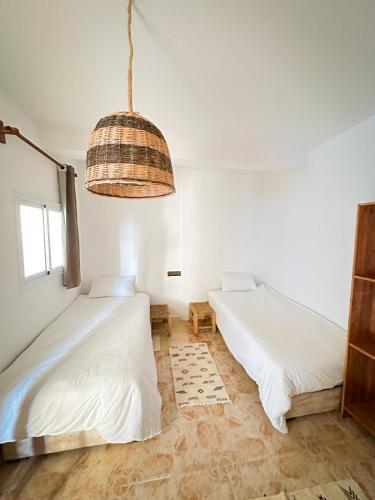 a bedroom with two beds and a pendant light at Eco Bay Surf Camp in Aourir