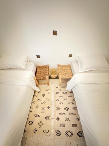 two white beds in a room with a rug at Eco Bay Surf Camp in Aourir