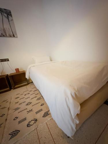a bedroom with a white bed with a rug at Eco Bay Surf Camp in Aourir