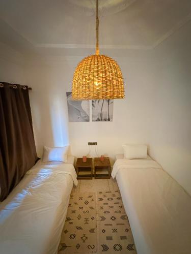 two beds in a room with a chandelier at Eco Bay Surf Camp in Aourir