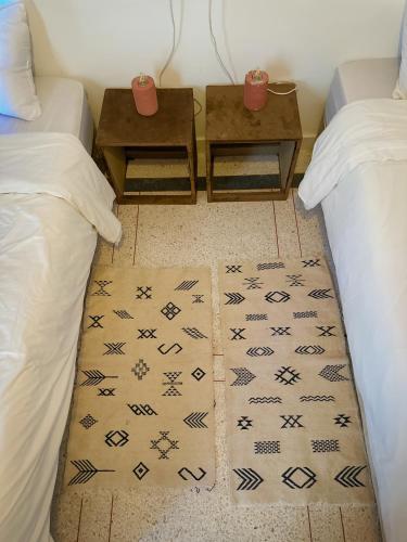 a room with two beds and two tables and a rug at Eco Bay Surf Camp in Aourir