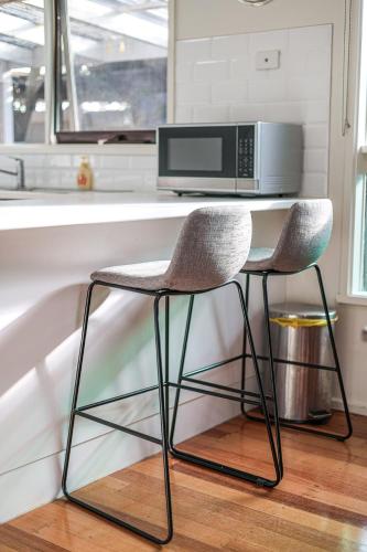 a kitchen with a counter with a microwave and two chairs at StayAU Newly Modern Comforts 3BRM Home Cranbourne in Cranbourne