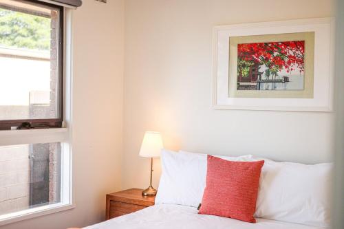 a bedroom with a bed with a red pillow and a window at StayAU Newly Modern Comforts 3BRM Home Cranbourne in Cranbourne