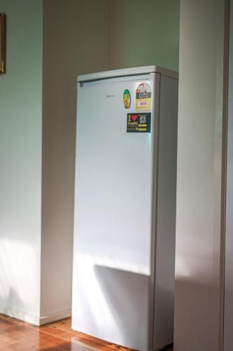 a white refrigerator freezer sitting in a room at StayAU Newly Modern Comforts 3BRM Home Cranbourne in Cranbourne