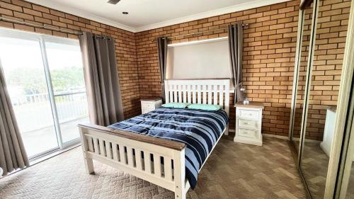 a bedroom with a bed and a brick wall at 'seaduced By Minnie in Minnie Water