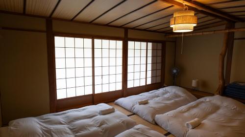 two white beds in a room with windows at Hakuba Hospitality Inn YUKINOSO in Hakuba