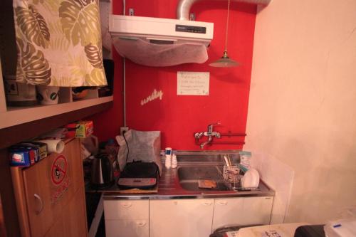 a small kitchen with a sink and a red wall at 2F - Vacation STAY 41690v in Okinawa City