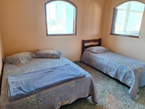 バーハ・デ・サン・ジョアンにあるCasa Aconchegante com Vista para o Mar em Rio das Ostrasの窓が2つある部屋にベッドが2つある