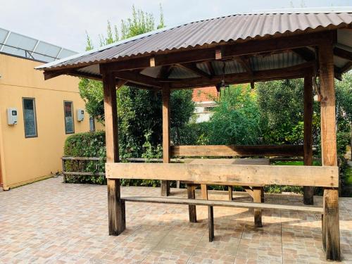 a wooden pavilion with two benches in a courtyard at Acogedor céntrico loft in Angol