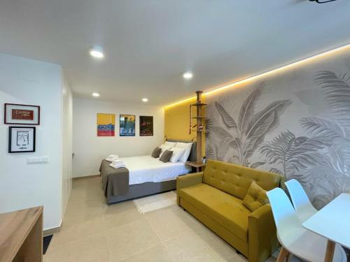 a bedroom with a bed and a yellow couch at Botique Studio - Casa El Sueño II in Vodnjan