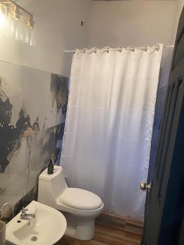 a bathroom with a white toilet and a sink at Joy & peace house in Tela
