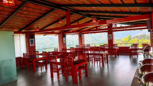 a restaurant with red chairs and tables with a view at Kodai Elliott in Kodaikānāl
