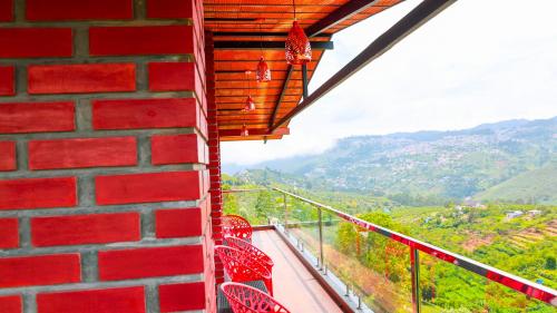 a red brick wall with red chairs on a balcony at Kodai Elliott in Kodaikānāl