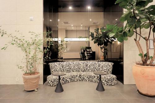 a room with a couch and two stools and plants at Aank Hotel Incheon Guwol in Incheon