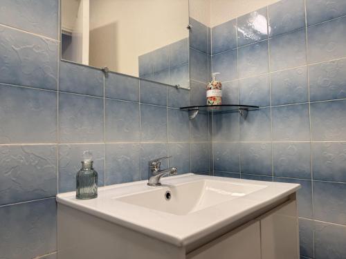 un bagno con lavandino, specchio e piastrelle blu di Studio Charmant au Coeur d'Excideuil - Animaux Bienvenus - FR-1-839-6 a Excideuil