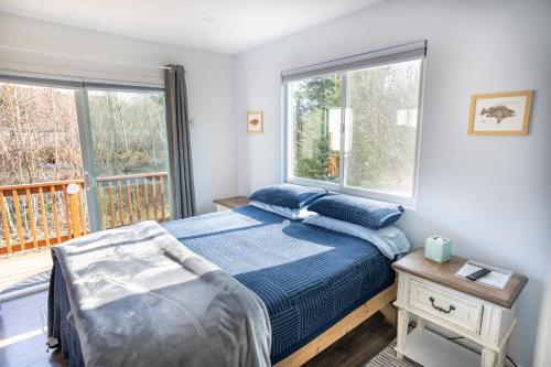 a bedroom with a bed and two windows at Glacier Creek Cabins in Seward