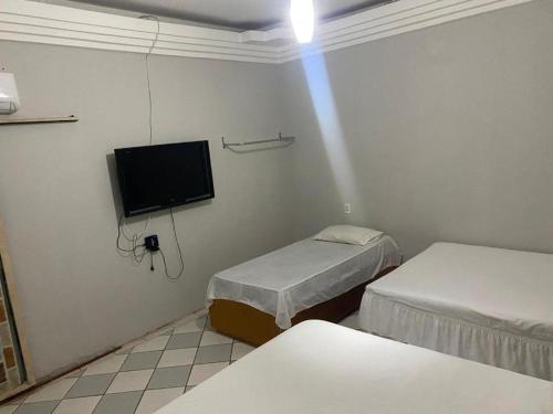 a room with two beds and a flat screen tv at Casa Piauí Hostel in Teresina