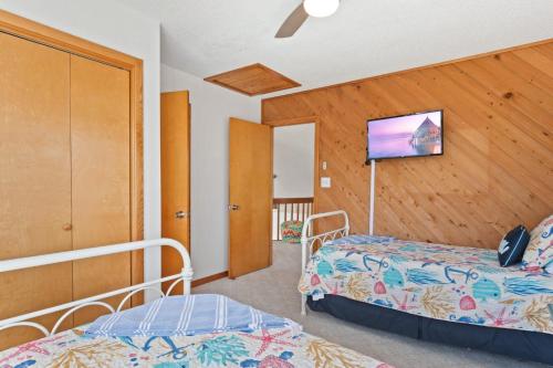a bedroom with two beds and a flat screen tv at 8074 - Sea Glass Charmer in Avon
