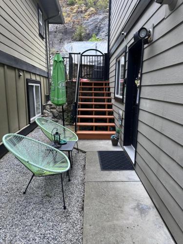 a patio with two chairs and a green umbrella at Separate entry sweet home in Victoria