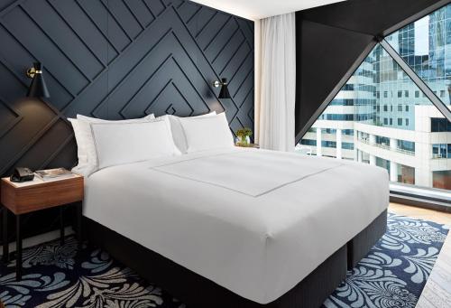a large white bed in a room with a window at West Hotel Sydney, Curio Collection by Hilton in Sydney