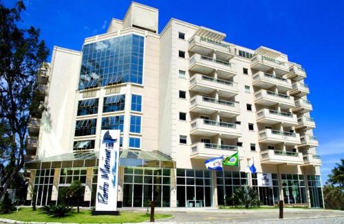 a tall white building with glass windows at Flat Porto Marina Mont Blanc in Mangaratiba