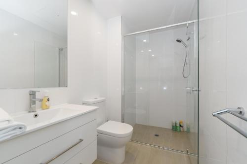 a white bathroom with a toilet and a shower at Convenient City Apartment in the Heart of Braddon - Hosted by Canstay in Braddon