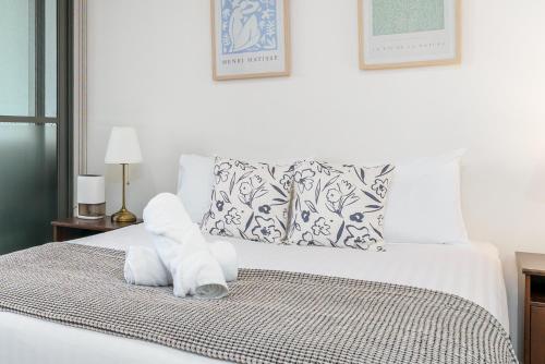 a white bed with a pile of towels on it at Convenient City Apartment in the Heart of Braddon - Hosted by Canstay in Braddon