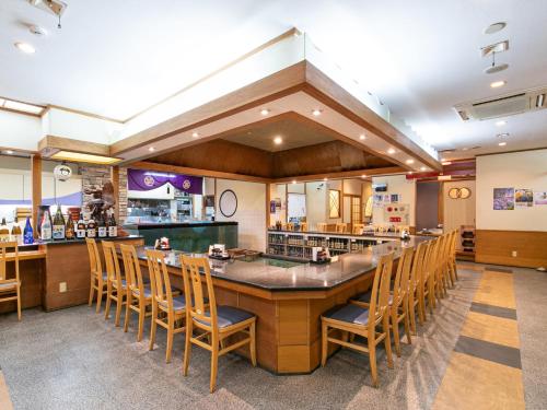 a restaurant with a large bar with wooden chairs at Hotel Verfort Hyuga in Hyuga