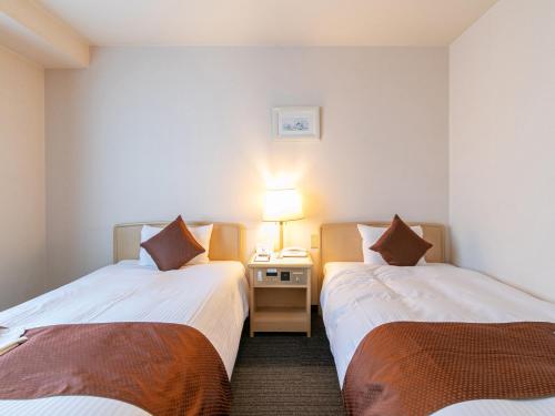a hotel room with two beds and a phone at Hotel Verfort Hyuga in Hyuga