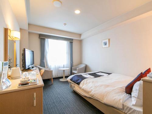 a hotel room with a bed and a television at Hotel Verfort Hyuga in Hyuga