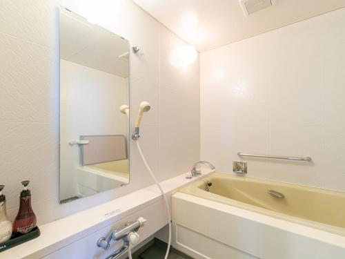a bathroom with a sink and a tub and a mirror at Hotel Verfort Hyuga in Hyuga
