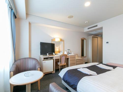 a hotel room with two beds and a desk at Hotel Verfort Hyuga in Hyuga