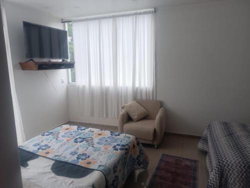 a bedroom with a bed and a chair and a window at Casa blanca in Santa María Atlihuetzián