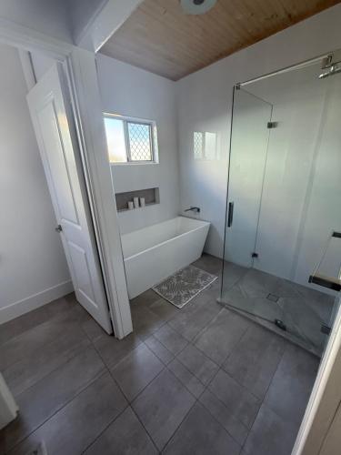 a bathroom with a tub and a glass shower at Beach house at Bangalee in Farnborough