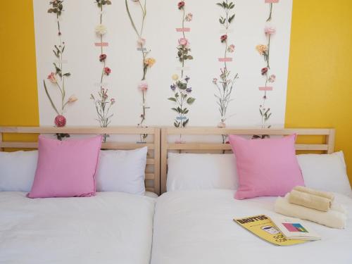 two beds in a room with flowers on the wall at Guesthouse HOALOHA 4 SEASONS in Chino