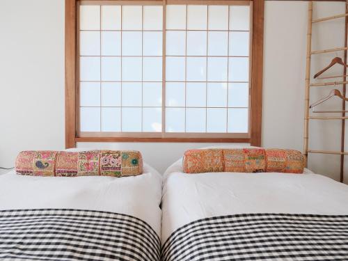 two beds in a room with a window at Guesthouse HOALOHA 4 SEASONS in Chino