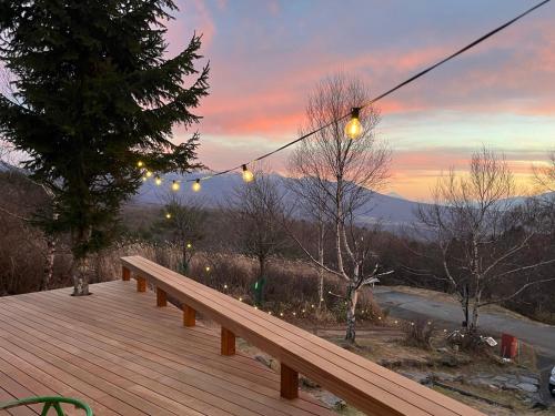 a wooden bench on a deck with a sunset at Guesthouse HOALOHA 4 SEASONS in Chino