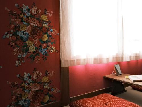 a wall with a flower mural on a red wall at Guesthouse HOALOHA 4 SEASONS in Chino