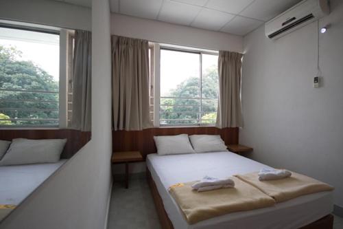 two beds in a room with two windows at Bahagia Stay Georgetown in George Town