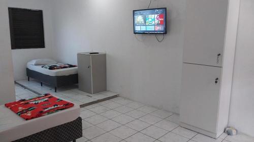 a room with a tv on the wall and a bed at Pousada do Trabalhador Canoas in Canoas